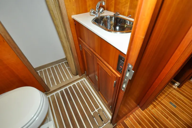 Night Train Yacht Photos Pics Hinckley Sou'wester 51 yacht bathroom interior, featuring wooden cabinetry and stainless steel sink, 1986 model.
