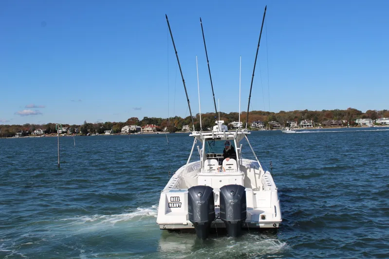 Reel Heavy Yacht Photos Pics 2009 Everglades 320 Center Console boat on water, dual engines, fishing rods, scenic background.