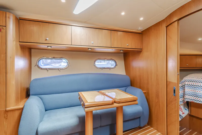 Worked The Plan Yacht Photos Pics 2009 Tiara Yachts 3900 Sovran interior with blue sofa, wooden cabinets, and table.