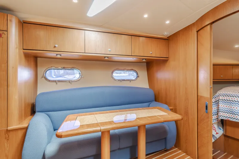 Worked The Plan Yacht Photos Pics 2009 Tiara Yachts 3900 Sovran interior with blue sofa, wooden cabinets, and dining table.
