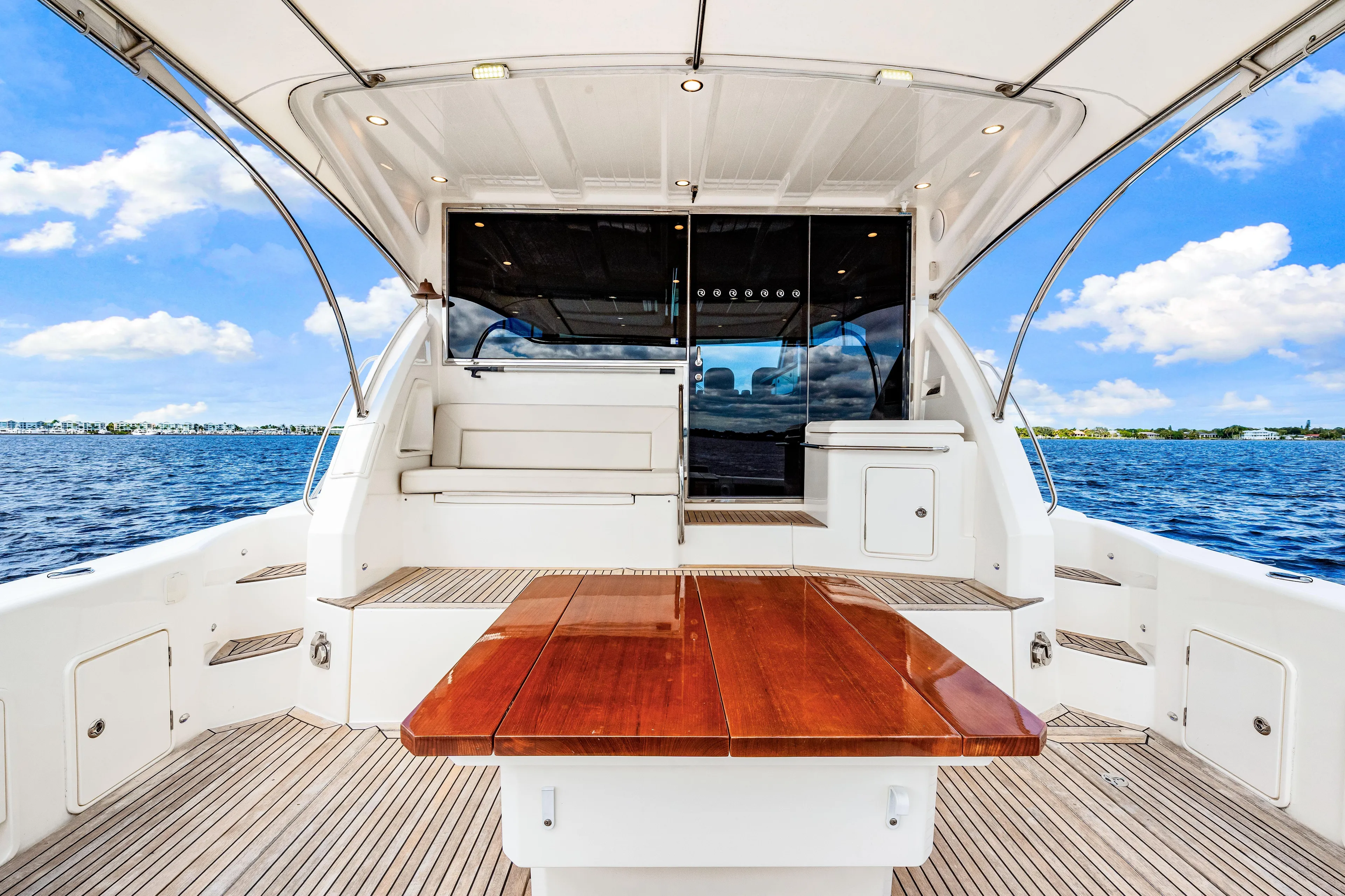 Escape Pod Yacht Photos Pics 2015 Riviera 565 SUV yacht deck with wooden table, ocean view, and clear blue sky.