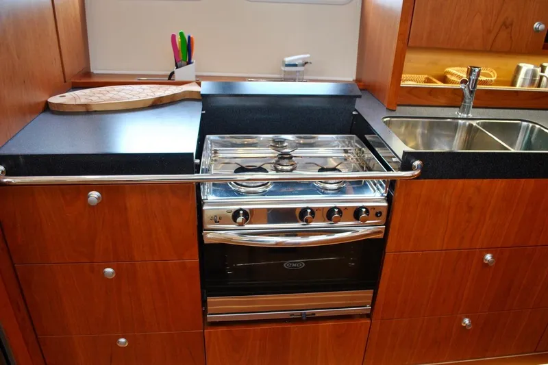 First Light Yacht Photos Pics Modern kitchen in 2017 Hanse 505 yacht with stove, sink, and wooden cabinetry.