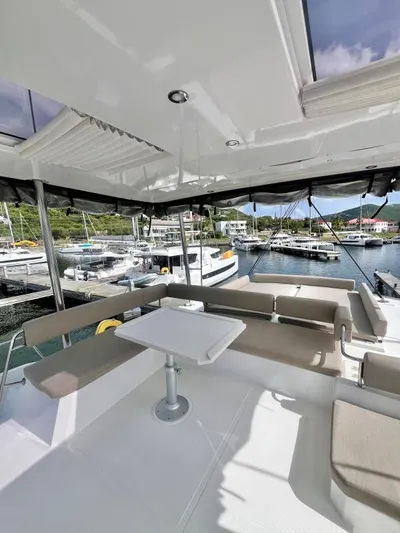Sea Dog Yacht Photos Pics Spacious deck of 2023 Bali 4.6 yacht with seating and table, docked at marina.
