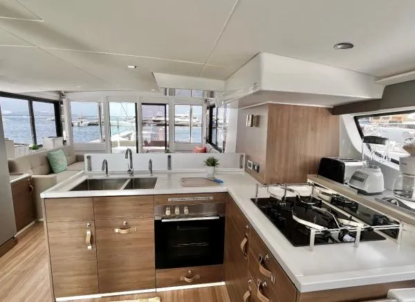 Sea Dog Yacht Photos Pics Modern kitchen interior on a 2023 Bali 4.6 yacht, featuring wood cabinetry and ocean views.