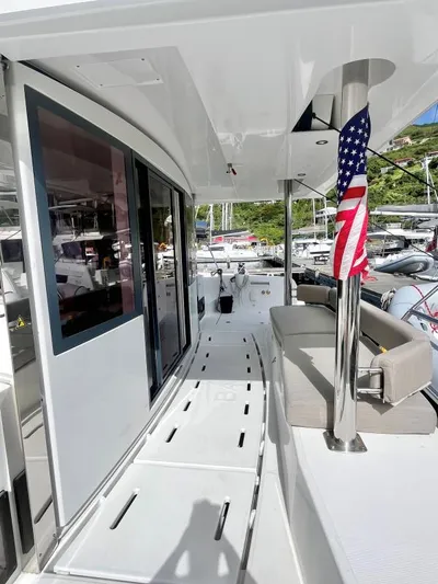 Sea Dog Yacht Photos Pics Modern 2023 Bali 4.6 yacht deck with seating and American flag, docked at marina.