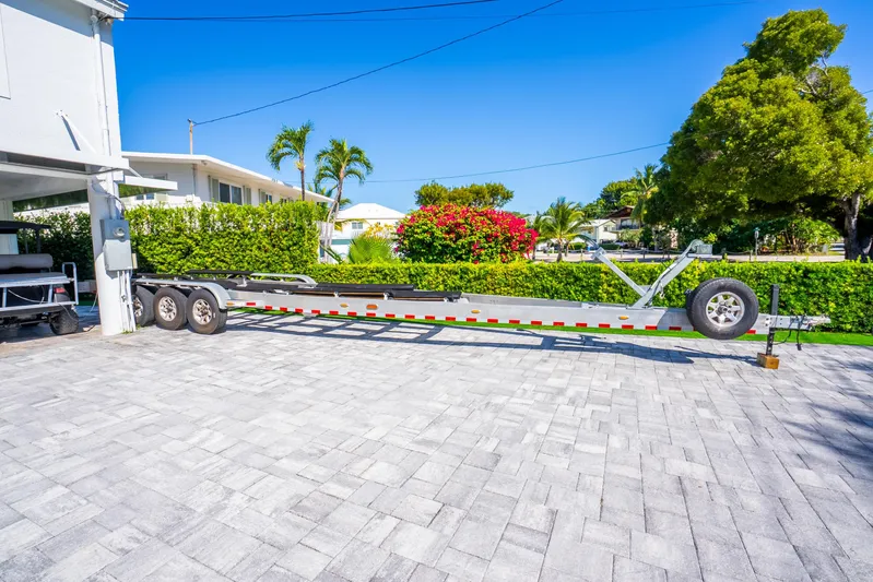  Yacht Photos Pics Trailer for 2016 Yellowfin 36 Offshore boat on paved driveway, surrounded by greenery.