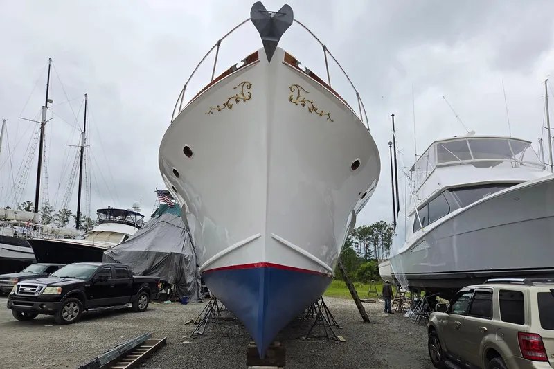 Windrush Yacht Photos Pics 1966 Trumpy 55 yacht in dry dock, surrounded by other boats and vehicles.