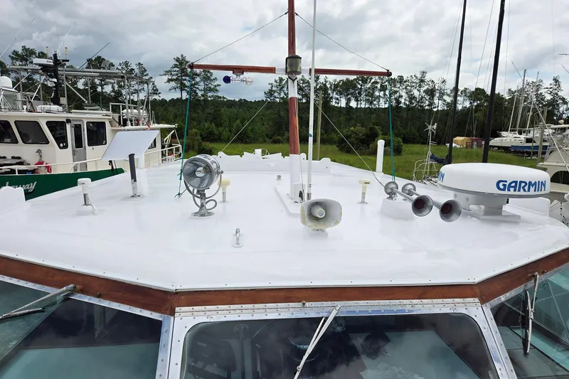 Windrush Yacht Photos Pics 1966 Trumpy 55 yacht with navigation equipment on deck, surrounded by other boats and trees.