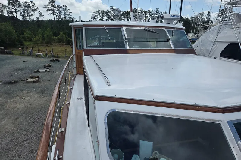 Windrush Yacht Photos Pics 1966 Trumpy 55 yacht on land, showcasing deck and cabin, surrounded by trees.