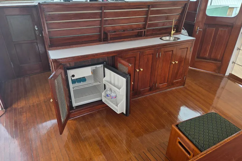 Windrush Yacht Photos Pics Vintage 1966 Trumpy 55 yacht interior with wooden cabinetry, mini fridge, and sink.