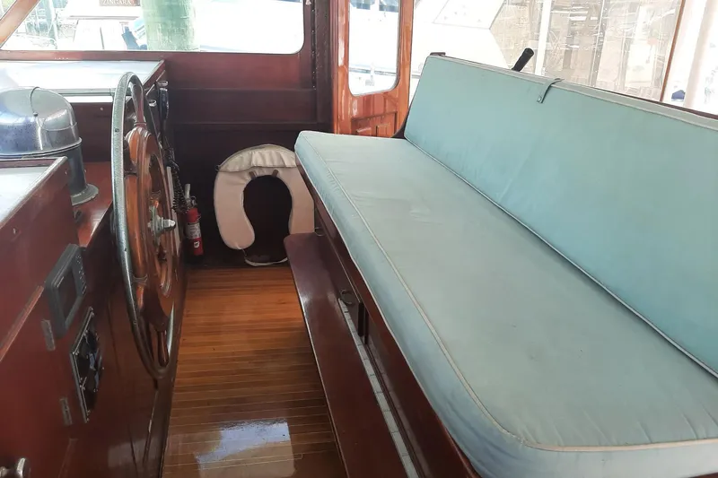 Windrush Yacht Photos Pics Interior of a 1966 Trumpy 55 boat with wooden helm and blue seating.