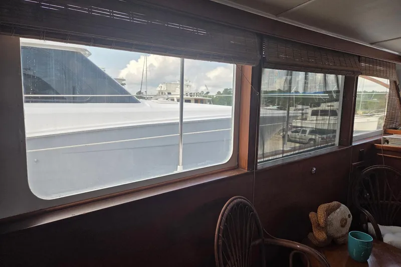 Windrush Yacht Photos Pics Interior view of 1966 Trumpy 55 yacht with large windows and wicker chairs.