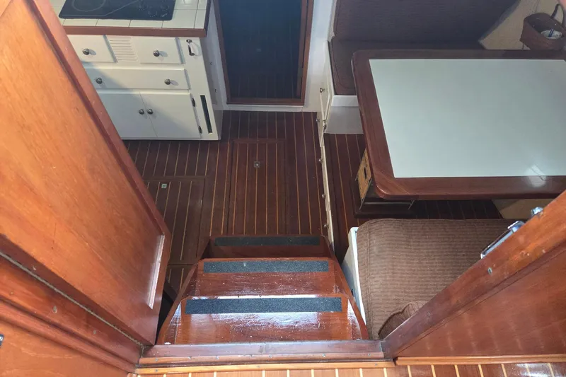 Windrush Yacht Photos Pics Interior of a 1966 Trumpy 55 boat, featuring wooden flooring and a compact dining area.