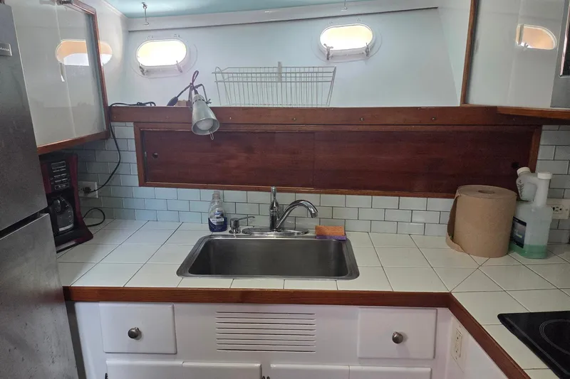 Windrush Yacht Photos Pics Compact kitchen in a 1966 Trumpy 55 yacht with sink, appliances, and porthole windows.