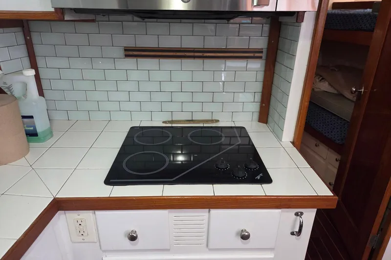 Windrush Yacht Photos Pics Vintage 1966 Trumpy 55 yacht kitchen with modern stovetop and tiled backsplash.