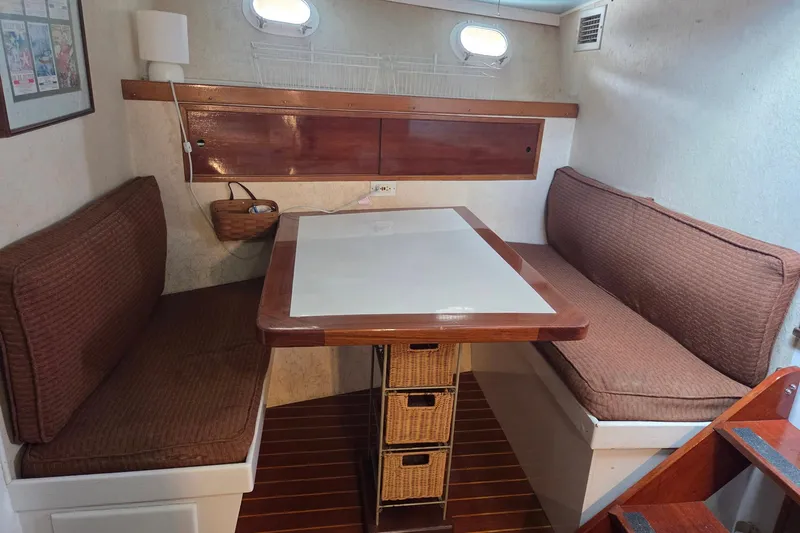 Windrush Yacht Photos Pics Cozy dining area in a 1966 Trumpy 55 yacht with cushioned seating and wooden table.