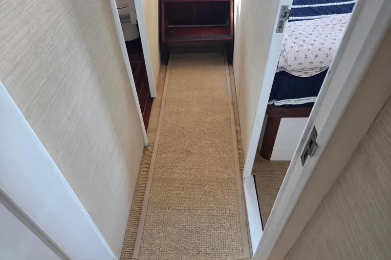 Windrush Yacht Photos Pics Narrow hallway inside a 1966 Trumpy 55 yacht, featuring carpet and adjacent rooms.