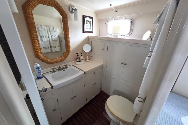 Windrush Yacht Photos Pics Vintage 1966 Trumpy 55 yacht bathroom with sink, mirror, and porthole window.