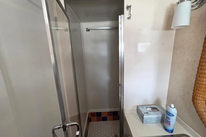 Windrush Yacht Photos Pics Bathroom with glass shower, wicker basket, and cleaning supplies on counter. Trumpy 55, 1966.