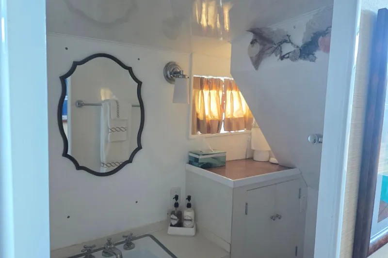 Windrush Yacht Photos Pics Vintage 1966 Trumpy 55 yacht bathroom with mirror, sink, and window curtains.