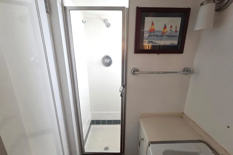 Windrush Yacht Photos Pics Compact bathroom with shower, nautical artwork, and towel rack on a 1966 Trumpy 55 yacht.