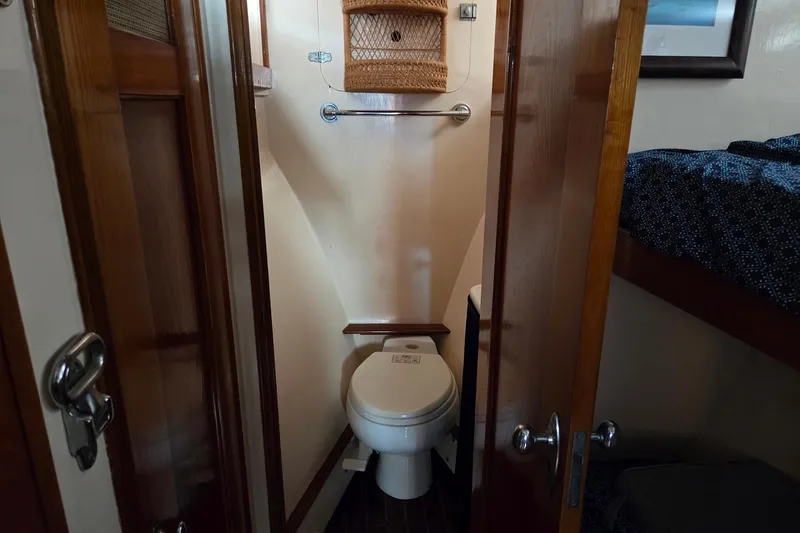 Windrush Yacht Photos Pics Compact bathroom in a 1966 Trumpy 55 yacht with wooden doors and cozy design.