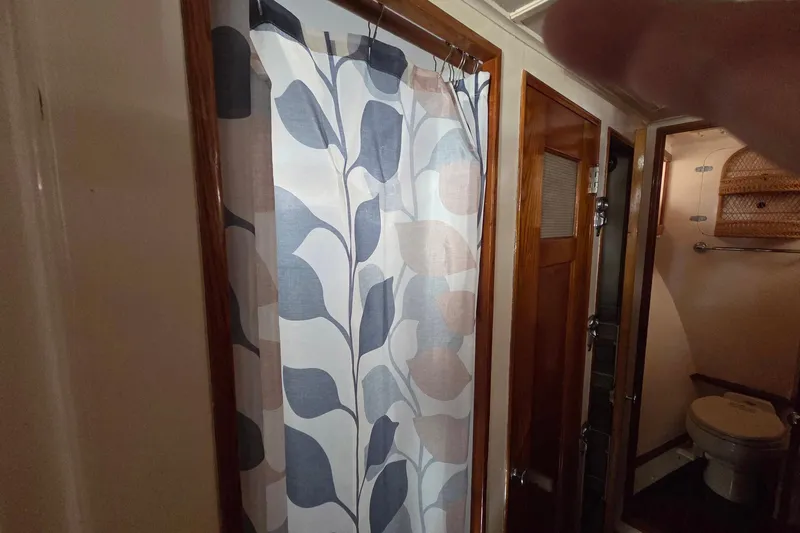 Windrush Yacht Photos Pics 1966 Trumpy 55 interior with floral shower curtain and wooden bathroom door.