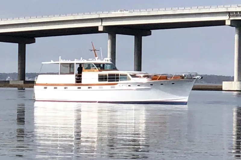 Windrush Yacht Photos Pics Classic 1966 Trumpy 55 yacht on calm water near a bridge.