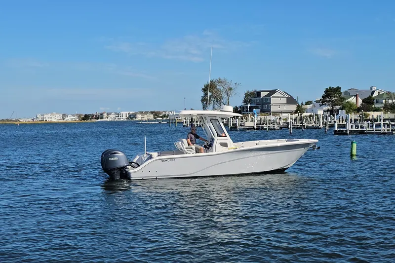  Yacht Photos Pics 2024 Sea Fox 268 Commander boat on calm water near a marina, clear blue sky.