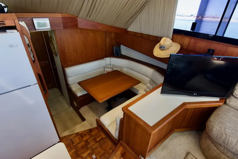 3 Hour Tour Yacht Photos Pics 1989 Viking Convertible yacht interior with dining area, TV, and wooden furnishings.