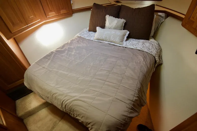 3 Hour Tour Yacht Photos Pics Cozy bedroom in 1989 Viking Convertible boat with plush bedding and wooden cabinets.