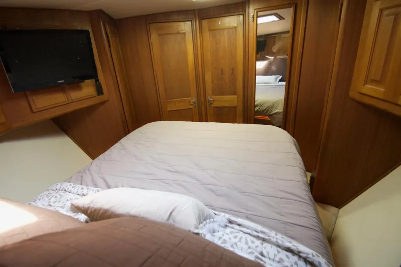 3 Hour Tour Yacht Photos Pics 1989 Viking Convertible yacht bedroom with wood paneling, bed, and TV.