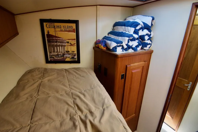 3 Hour Tour Yacht Photos Pics Cozy cabin interior of 1989 Viking Convertible with bed, Catalina Island poster, and folded blankets.