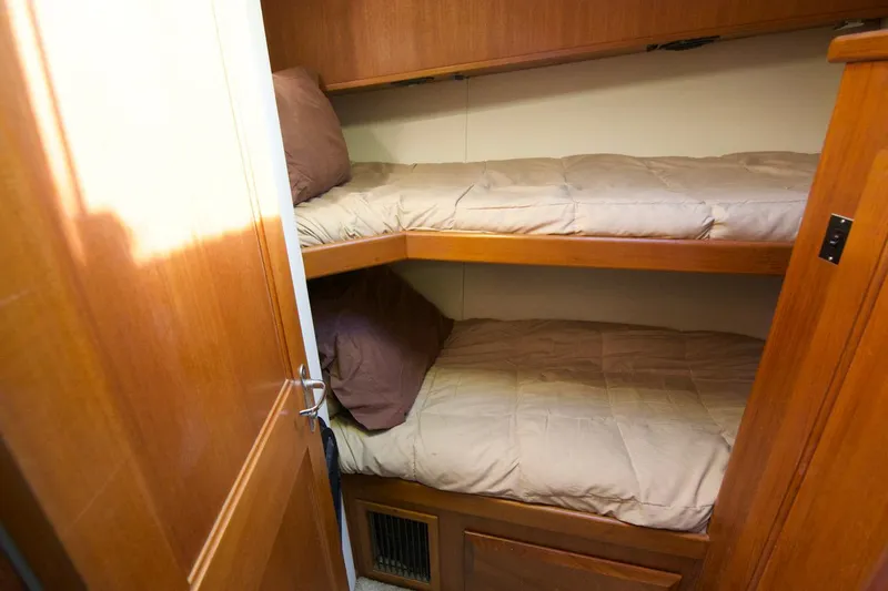 3 Hour Tour Yacht Photos Pics 1989 Viking Convertible boat interior with wooden bunk beds and beige bedding.