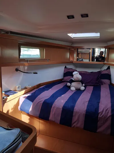  Yacht Photos Pics Cozy cabin interior of 2013 Beneteau Sense 43 sailboat with striped bedding and plush toy.