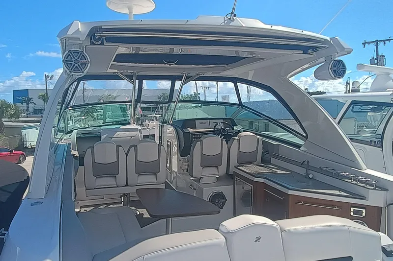350-004 - Brokerage Joe Yacht Photos Pics 2019 Four Winns H350 boat interior with seating, table, and helm under a clear blue sky.