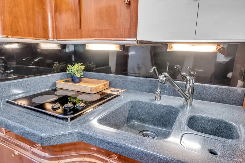  Yacht Photos Pics 1997 Sea Ray 500 Sundancer kitchen with stove, sink, and wooden decor.