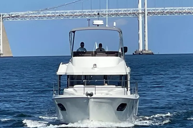 R&r Yacht Photos Pics 2023 Beneteau Swift Trawler 35 cruising under a bridge on open water.