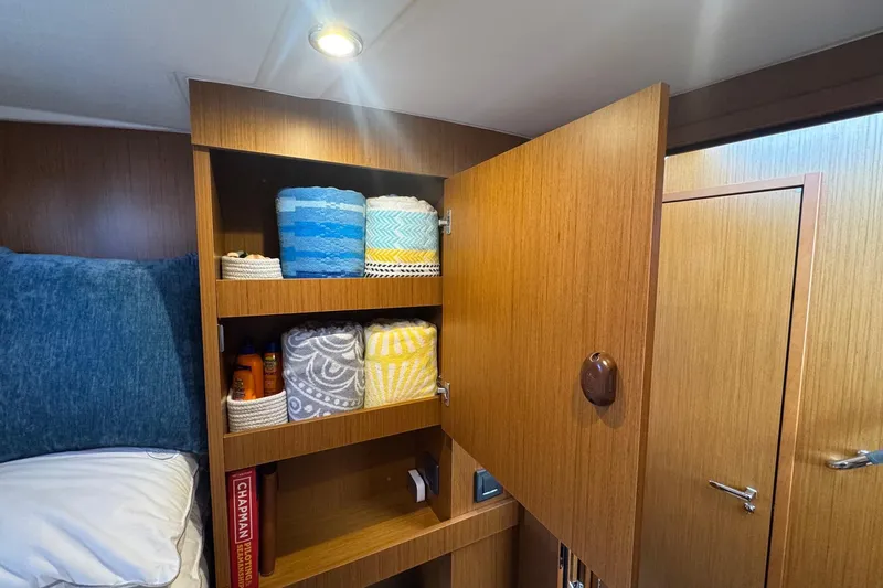R&r Yacht Photos Pics Interior of 2023 Beneteau Swift Trawler 35 with open wooden cabinet and neatly arranged towels.