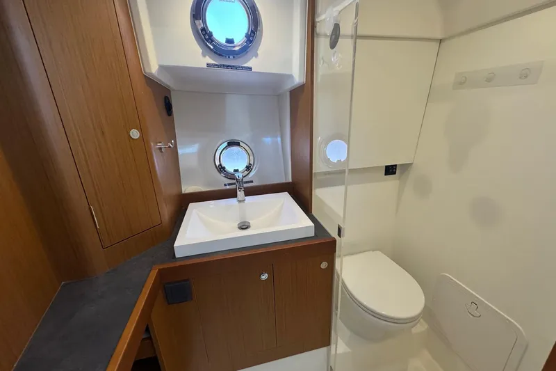 R&r Yacht Photos Pics Bathroom interior of 2023 Beneteau Swift Trawler 35, featuring sink, toilet, and porthole window.