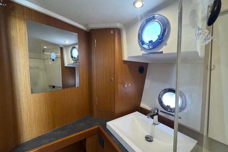 R&r Yacht Photos Pics 2023 Beneteau Swift Trawler 35 bathroom with wood accents and porthole windows.