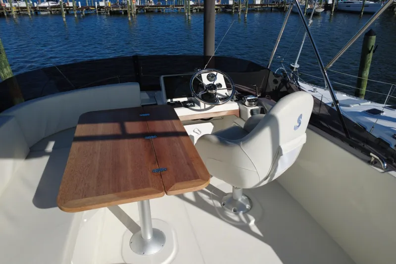 R&r Yacht Photos Pics 2023 Beneteau Swift Trawler 35 helm with wooden table and captain's chair, dockside view.