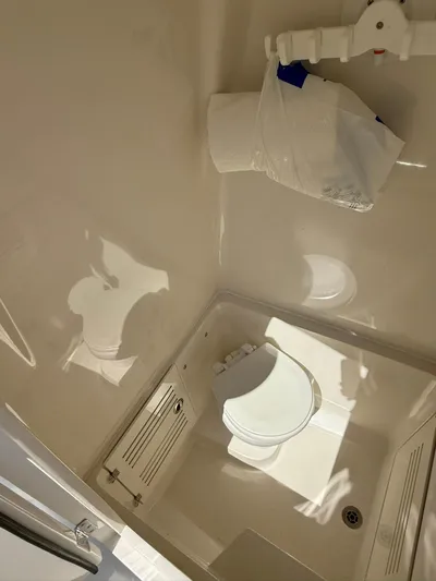  Yacht Photos Pics Compact bathroom in 2018 Jupiter 26 FS boat, featuring a toilet and storage compartment.