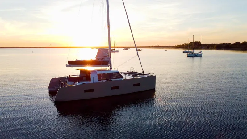  Yacht Photos Pics Sailing catamaran Vaan R4, 2025 model, at sunset on calm waters.