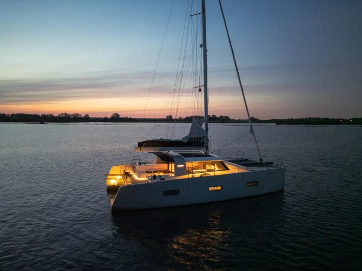  Yacht Photos Pics Sailing catamaran Vaan R4, 2025 model, illuminated at sunset on calm waters.