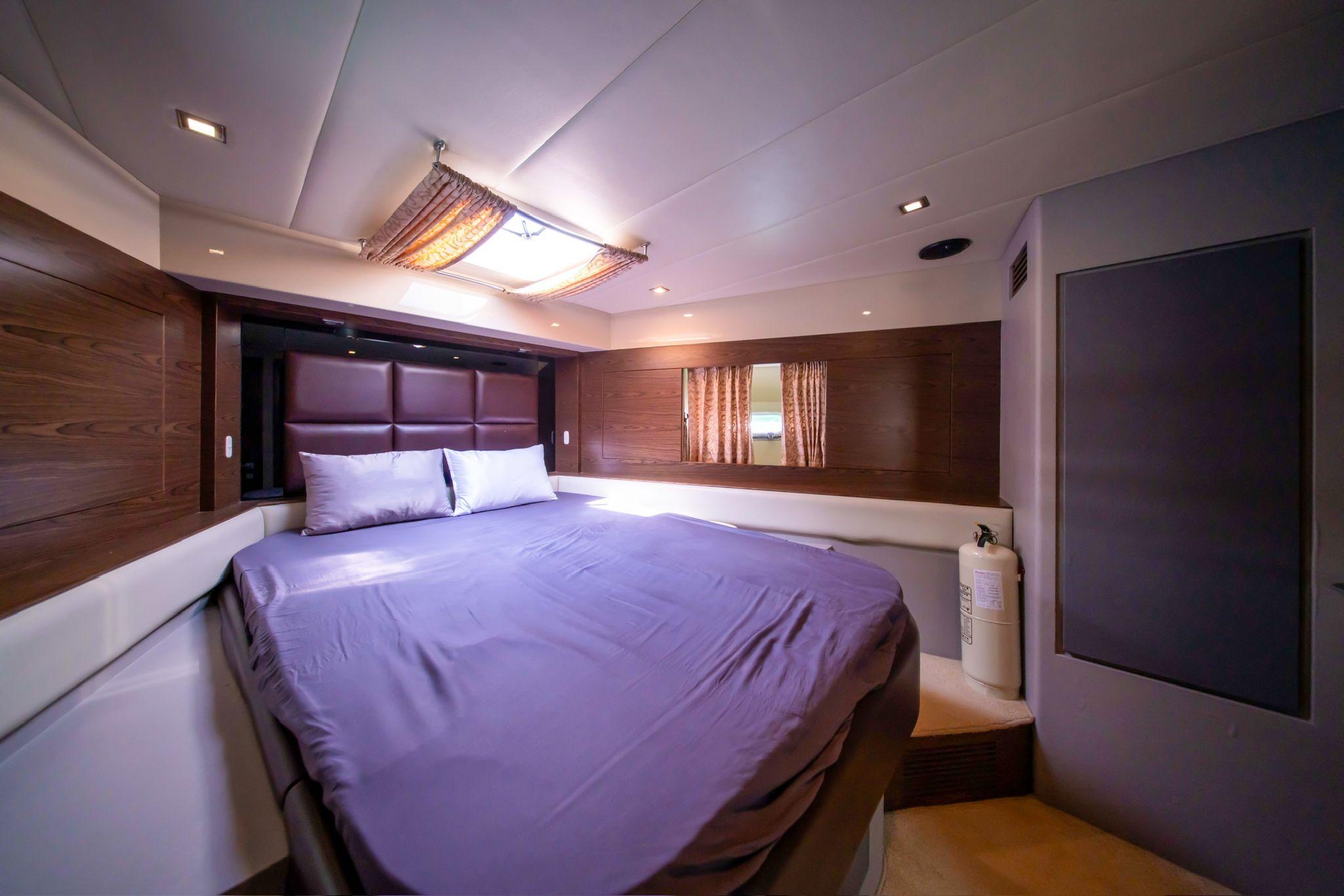 Luxurious bedroom interior in a 2011 Ruby 68 yacht, featuring a spacious bed and elegant wood paneling.