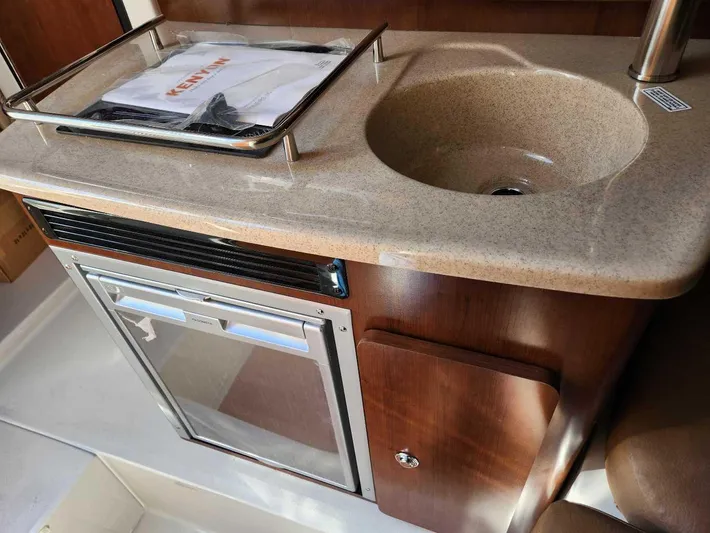  Yacht Photos Pics Compact kitchen area in the 2024 Crownline 280 CRX boat with sink and mini-fridge.