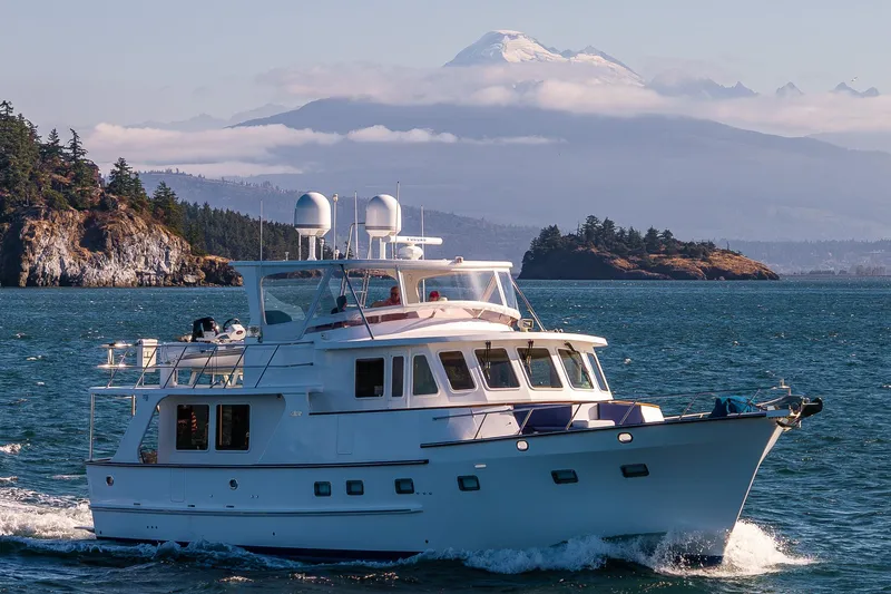 Flyin Low Yacht Photos Pics 2007 DeFever 56 yacht cruising in scenic coastal waters with mountainous backdrop.