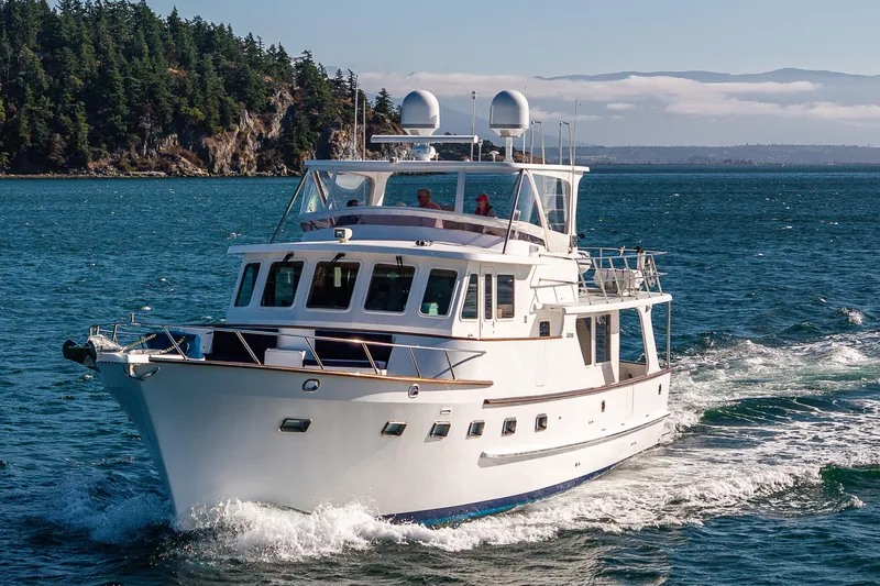 Flyin Low Yacht Photos Pics 2007 DeFever 56 yacht cruising on scenic blue waters near forested coastline.