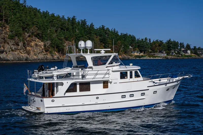 Flyin Low Yacht Photos Pics 2007 DeFever 56 yacht cruising near a forested coastline.